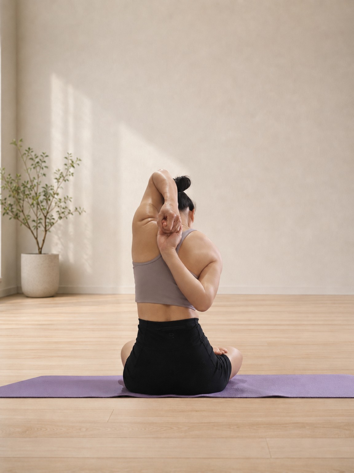 A woman practising a seated yoga stretch in a calm studio
